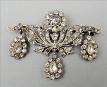 A Victorian/Edwardian paste set silver brooch The scrolling floral body issuing three drops, marks