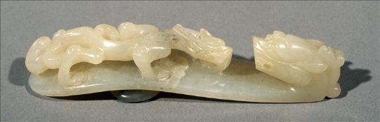 A Chinese carved jade belt hook Modelled with the figure of a dragon. 8.5 cms long. Generally in