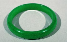 A Chinese carved jadeite bangle 7.5 cms diameter. Generally in good condition, expected wear.