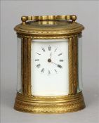 An oval brass cased miniature carriage clock The C-scroll swing handle above a white enamel dial