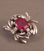 An Art Deco unmarked 18 ct white gold diamond an ruby brooch 1.5 cms wide. Overall good, some wear