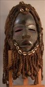 An African tribal mask With applied cowrie shells and rope twist hair and beard. The mask 25 cms