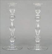 A pair of early 19th century clear glass candlesticks Each with spreading drip pans above a knop and