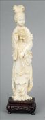 A Chinese carved figure of a young woman Modelled in flowing robes and holding a flower, standing on