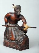 A late 19th/early 20th century carved wood figure of a Maori warrior Modelled crouching, holding a