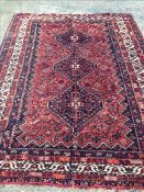 A Shiraz wool rug The wine red field enclosing a central pole medallion within geometric motifs,