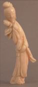 A Chinese carved coral figure Formed as Guanyin, holding a budding flower. 11.5 cms high. Some