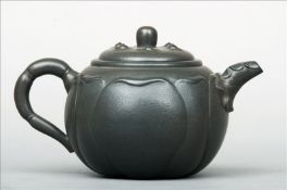 A Chinese Yixing pottery teapot The body lappet moulded, the cover with six encased beads, impressed