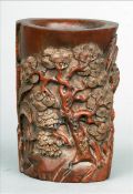 A Chinese carved wood brush pot Decorate in relief with figures in a rocky landscape. 13.5 cms high.