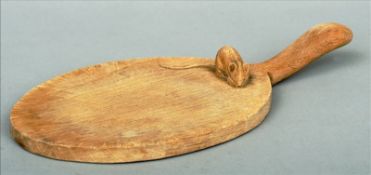 A Robert "Mouseman" Thompson oak cheeseboard Of paddle form, with carved mouse. 38 cms long.