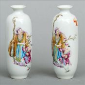 A pair of small Chinese porcelain vases Each decorated with a man holding a staff and a child a