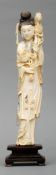 A carved ivory figure of a lady Modelled in a flowing gown and holding a flowering branch, mounted