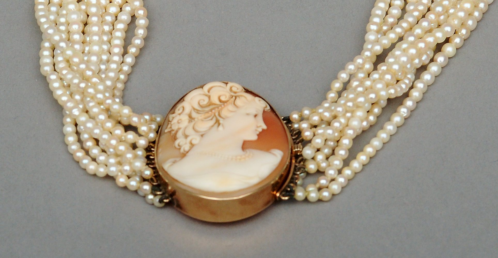 A late 19th/early 20th century unmarked gold mounted cameo set pearl necklace The ten strand