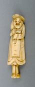 A Japanese 19th century carved ivory netsuke Modelled as a Westerner carrying a sack over one