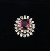 An 18 ct yellow gold ruby and diamond cluster ring The central ruby bordered by two rows of
