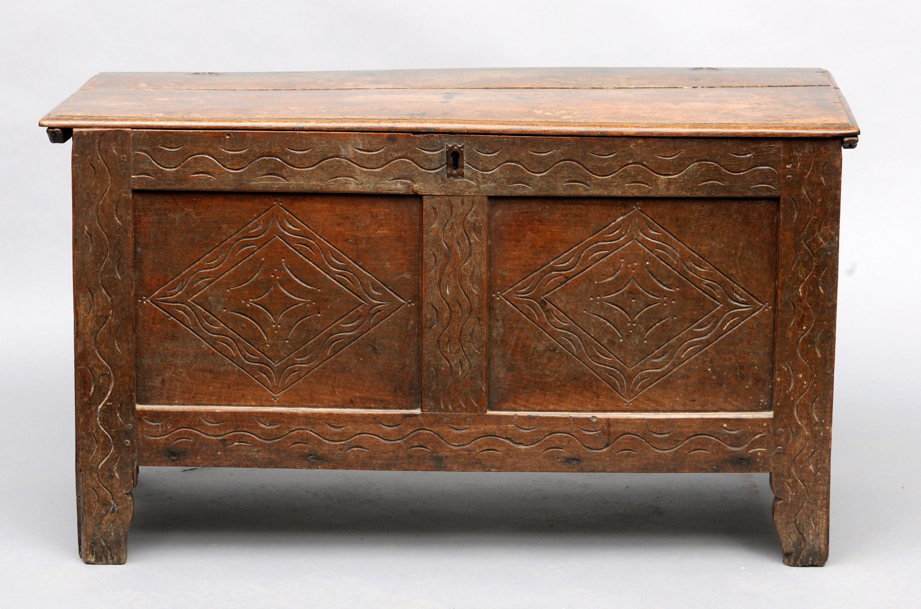 An 18th century carved oak panelled coffer The rectangular hinged top above a twin panelled front,