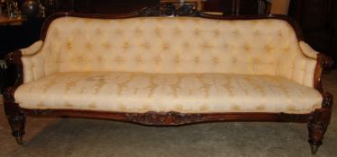 A Victorian walnut framed settee The scroll carved back rail above the upholstered button back and