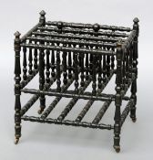 A Victorian ebonised Canterbury Of turned construction with brass caps and castors. 45 cms wide.