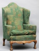 An 18th century style wing backed armchair The green upholstered chair with a carved frieze,