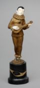 A cold painted bronze and ivory figure of a harlequin playing a lute Standing on a marble plinth