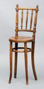 An Edwardian bentwood child’s correction chair The curved top rail with two acorn finials above