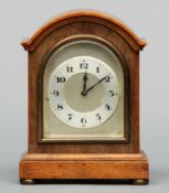 A small Edwardian walnut mantel clock The domed top above a silvered dial with Arabic numerals,