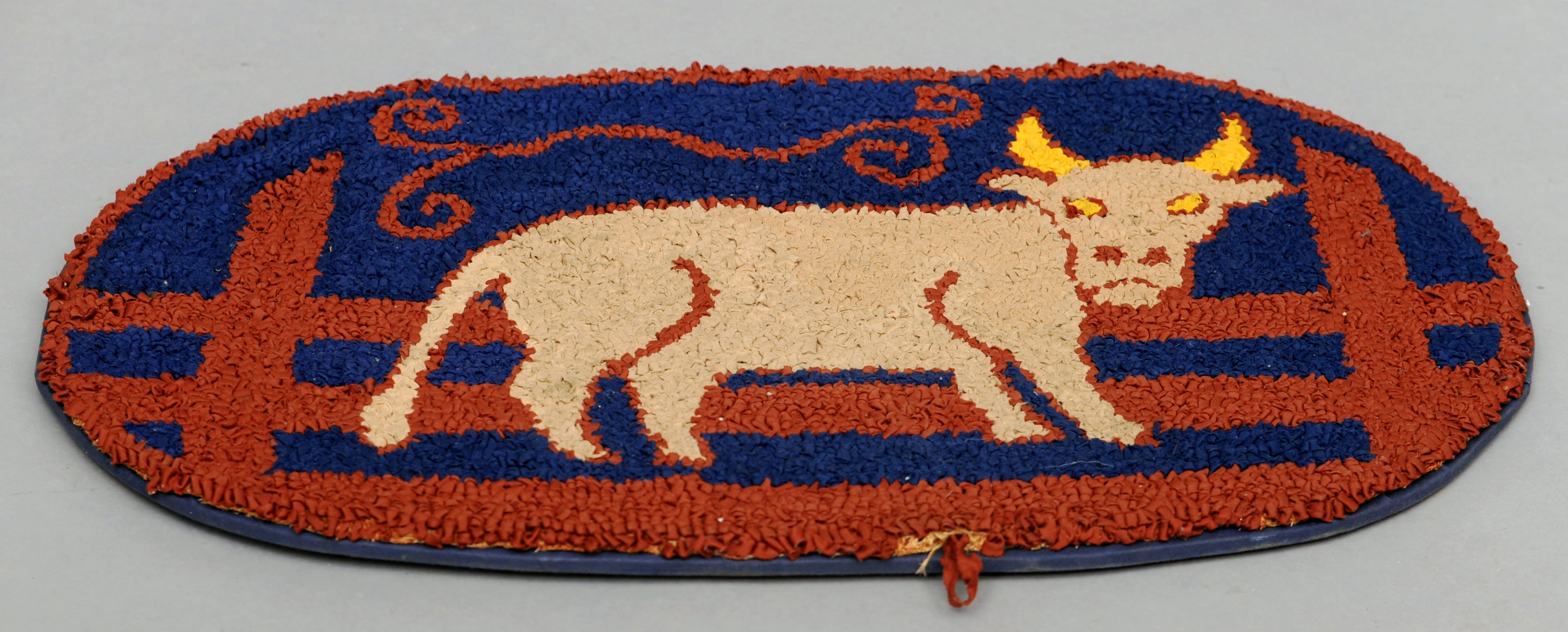 A late 19th/early 20th century hooked rag rug Centred with the figure of a bull. 87 cms wide.