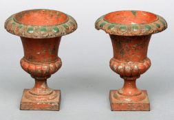 A pair of cast iron and painted garden urns Of typical form. 30 cms high. (2)Generally in good