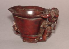 A Chinese carved hardwood libation cup Decorated with, and the handle modelled as, mythical