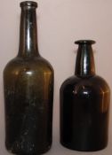 An 18th century blown green glass bottle Together with another. The former 27.5 cms high. (2)