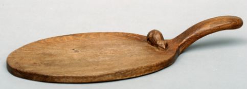 A Robert “Mouseman” Thompson azed oak cheeseboard Of paddle form with a single carved mouse. 37.5