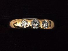 An 18 ct gold three stone diamond band The central stone approximately 0.25 carat.