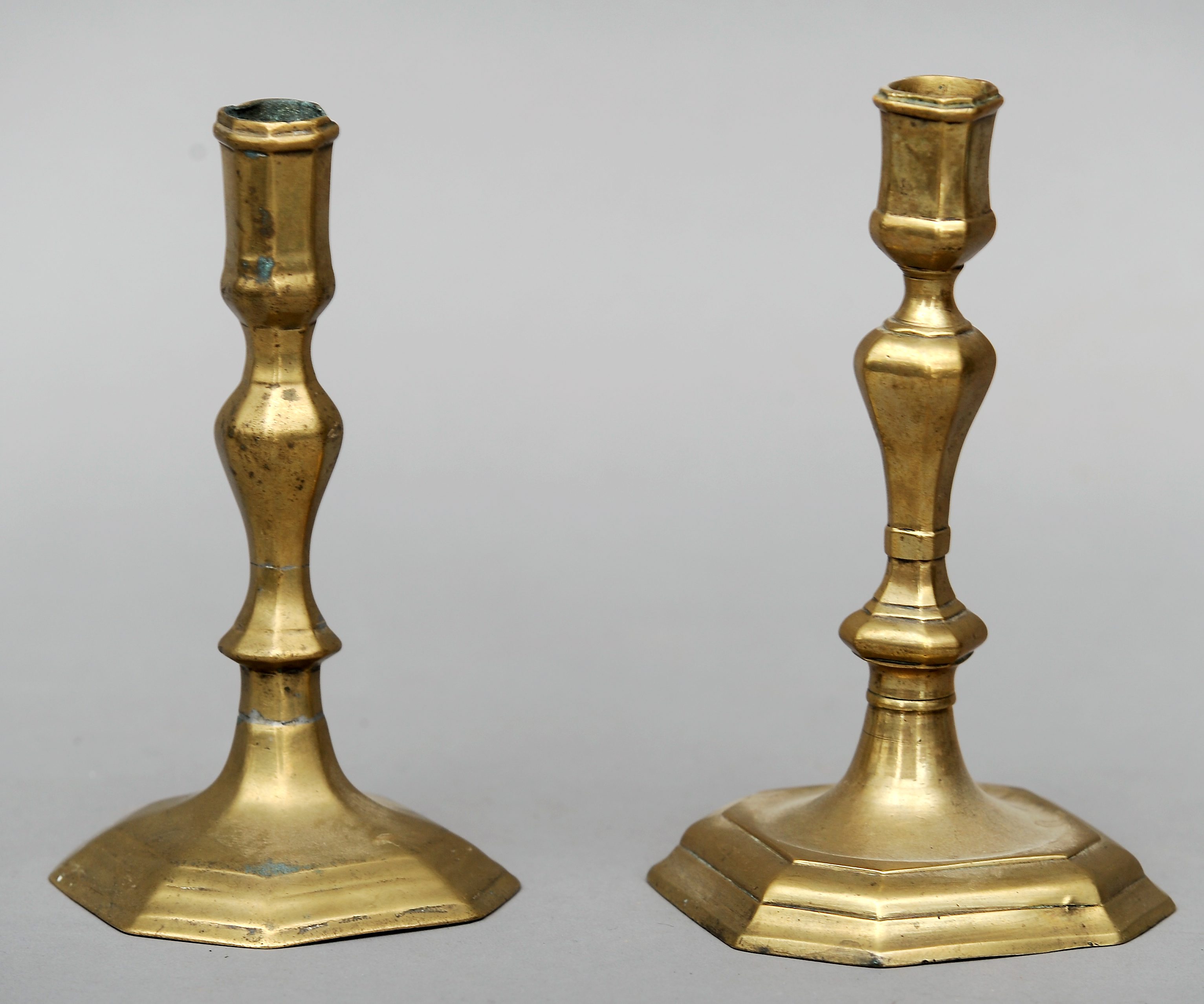 Two similar 18th century brass candlesticks Each of bulbous tapering form, standing on domed stepped
