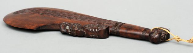A Maori type Wahika hand club With carved decoration and abalone shell inserts. 42 cms high.