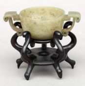 A Chinese carved jade twin handled bowl and stand Decorated with stylised dragons. 10.5 cms wide.