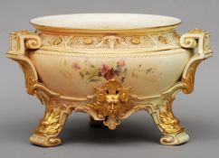 A Royal Worcester blush ivory ground jardiniere The flared rim above gilt rams mask panels and three