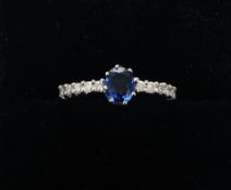 An 18 ct white gold sapphire and diamond ring The central oval cut sapphire flanked to either side