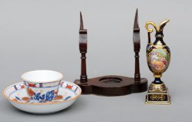 An overglazed blue and iron red decorated tea bowl and saucer, a carved hardwood stand and a
