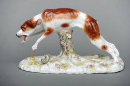 A late 19th/early 20th century Continental ceramic model of a hound Modelled leaping a tree stump,