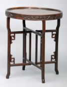 A Chinese carved hardwood folding side table The dished circular top carved to the frieze with