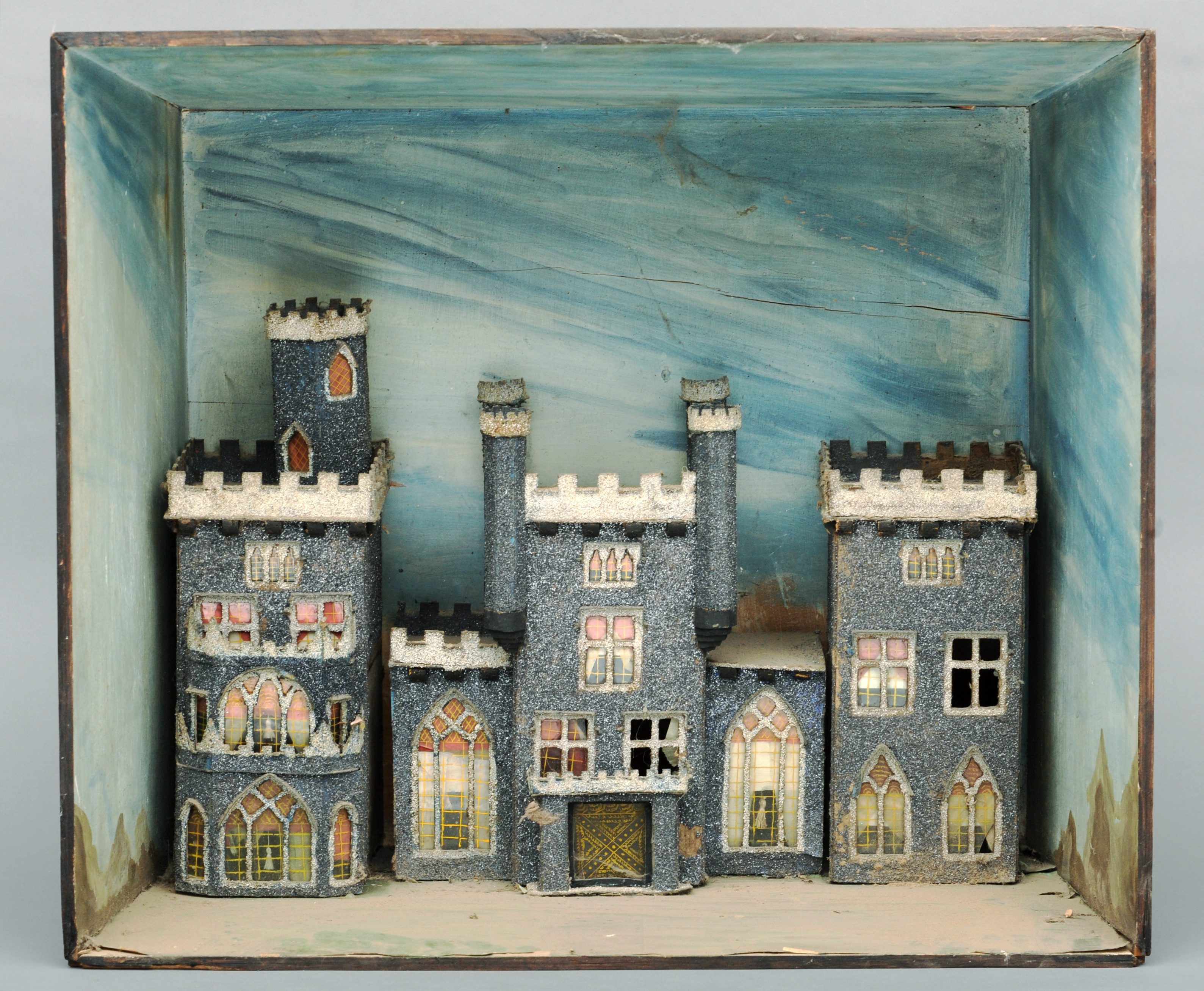 A 19th century decorated cardboard diorama of a castle Housed within a naturalistically painted open