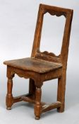 An 18th century oak child’s chair The moulded top rail above a serpentine frieze, supported by