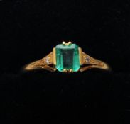 An 18 ct white gold emerald and diamond ring The central emerald flanked by two small diamonds.