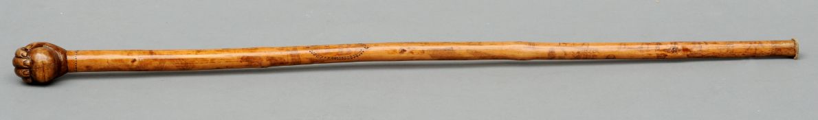 A 19th century penwork decorated walking stick The handle formed as a clenched fist holding a