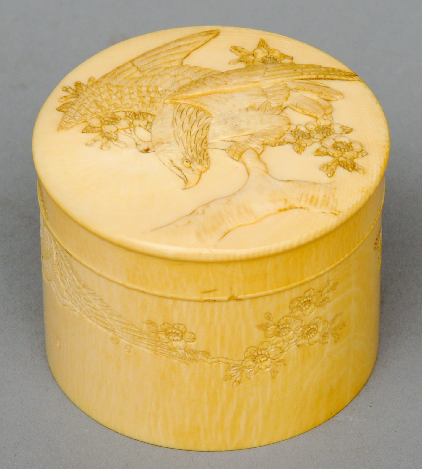 A late 19th century Japanese carved ivory box and cover Of cylindrical form, the lid decorated