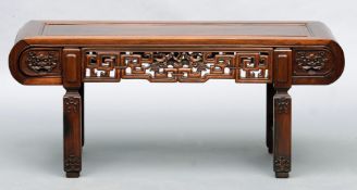 A Chinese carved hardwood bench The panelled seat above a carved and pierced gallery, standing on