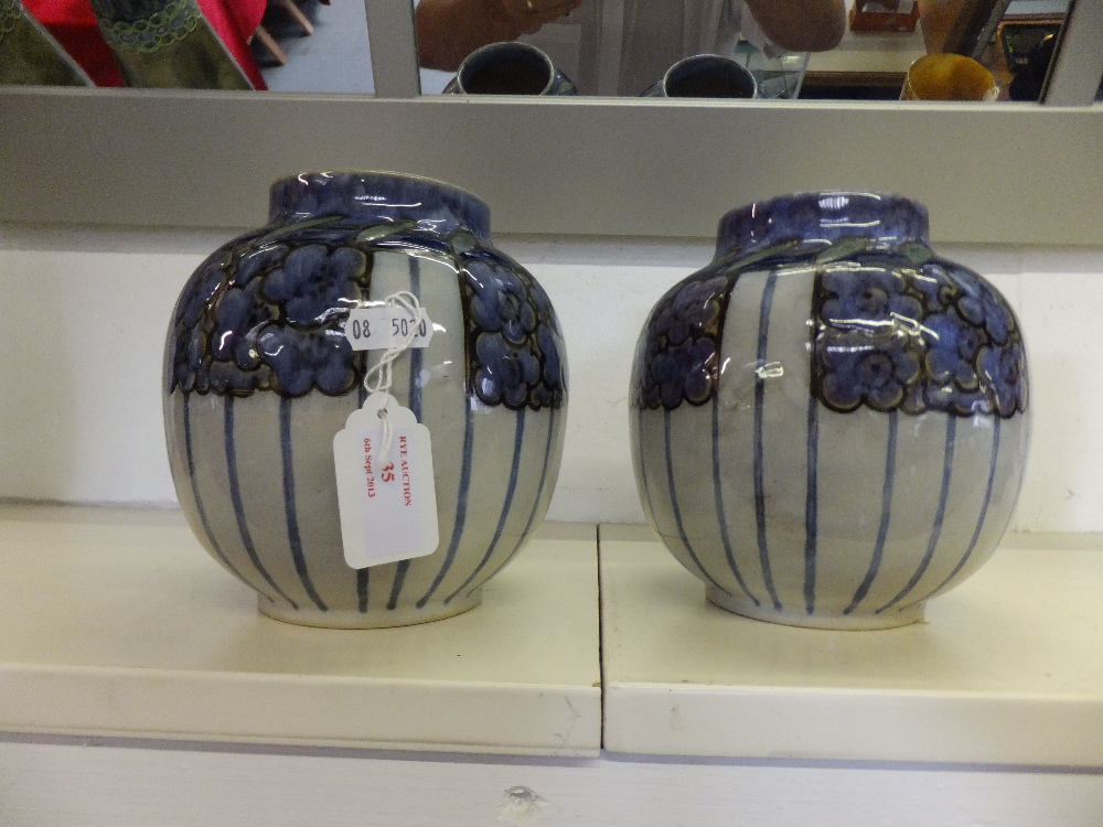 A pair of Royal Doulton stoneware squat vases with hand painted floral decoration signed to base
