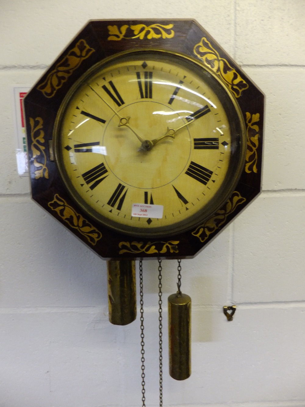 An octagonal mahogany cased wall clock and pendulum