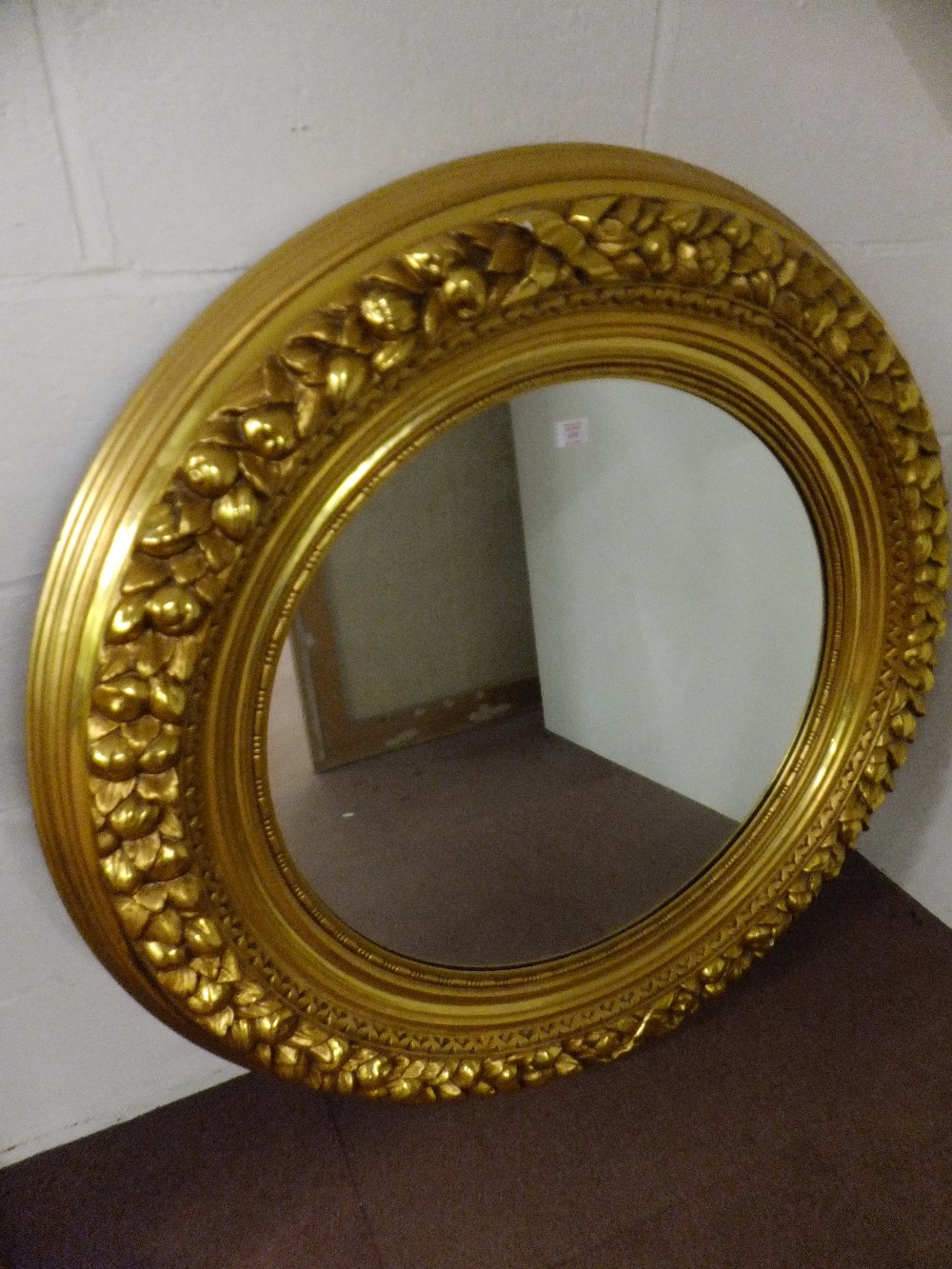 A mid-19th century round gilt and polychrome mirror having fruit and leaf carved decoration