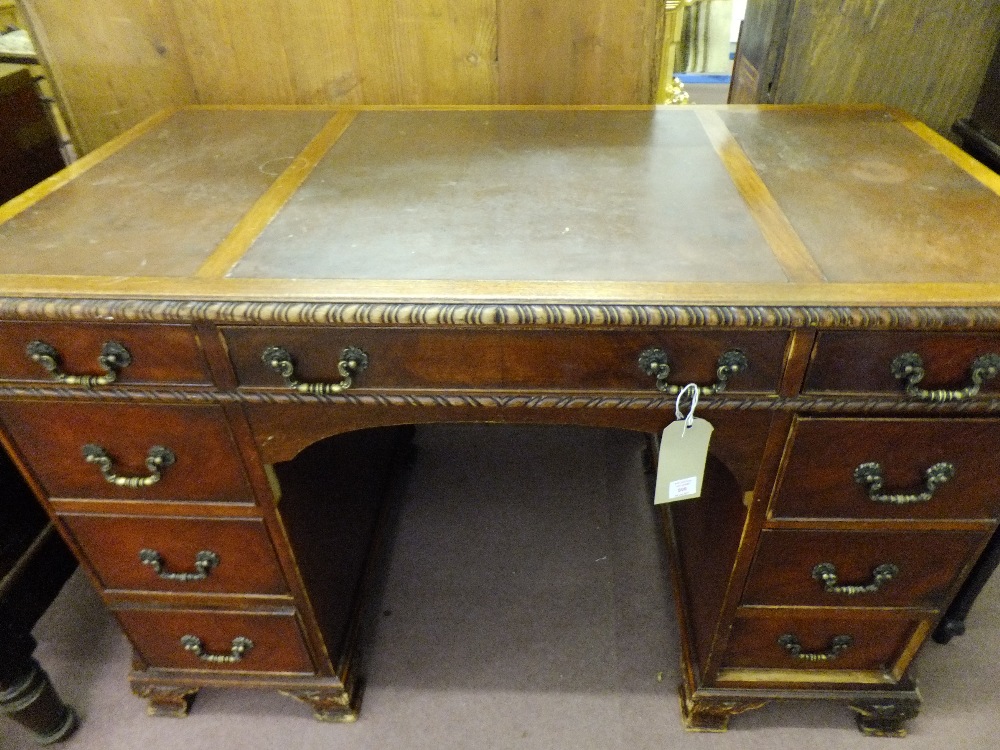 A mahogany pedestal desk having central drawer flanked by eight short drawers the top with leathered